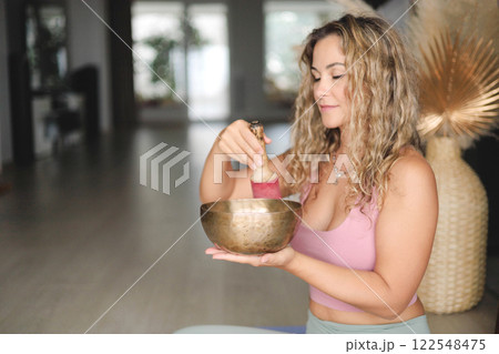 Yoga woman with singing meditation bowl enjoy sound with closed eyes closeup Yoga woman with singing meditation bowl enjoy sound with closed eyes closeup 122548475