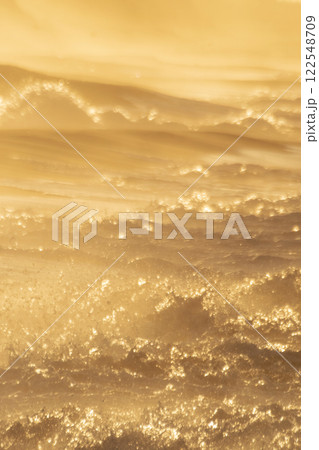 夕陽に染まる浜辺の荒波 122548709