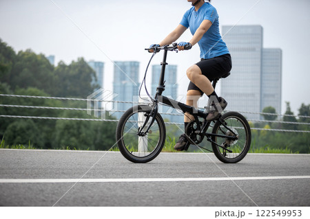 Riding a fold bike with modern city in the distrance Riding a fold bike with modern city in the distrance 122549953