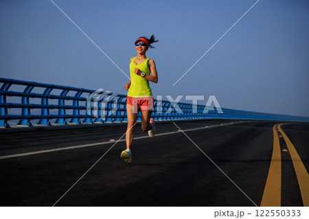 Fitness woman runner running on seaside bridge 122550333