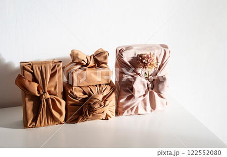 Gift boxes wrapped in reusable fabric, promoting waste reduction and sustainable gifting ideas. Gift boxes wrapped in reusable fabric, promoting waste reduction and sustainable gifting ideas. 122552080