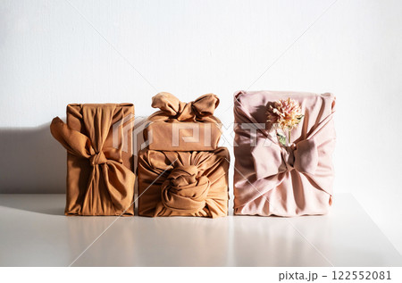 Gift boxes wrapped in reusable fabric, promoting waste reduction and sustainable gifting ideas. 122552081