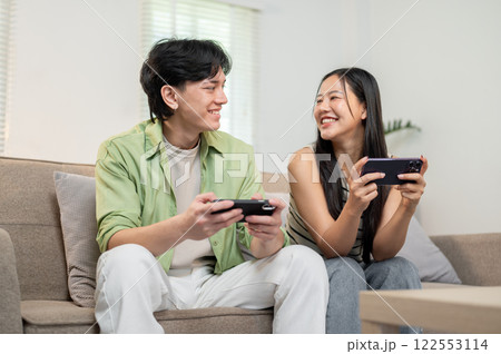 A lovely Asian couple enjoying playing a mobile game on their smartphones. 122553114