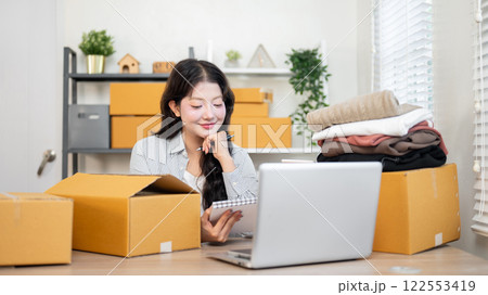 A satisfied Asian female online clothing shop owner is happy with the items ordered from her website 122553419