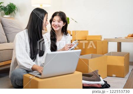 Female online business owners are working in the living room, packing goodies into cardboard boxes. Female online business owners are working in the living room, packing goodies into cardboard boxes. 122553730