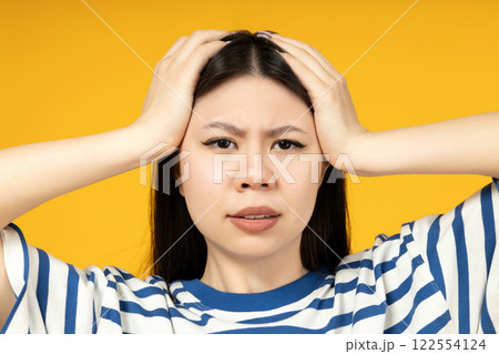 A girl of Asian appearance, on a yellow background. A girl of Asian appearance, on a yellow background. 122554124