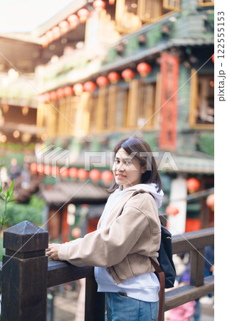 woman traveler visiting in Taiwan, female Tourist with backpack sightseeing at Jiufen Old Street village with Tea House background. Popular landmarks and attractions near Taipei City. Travel concept woman traveler visiting in Taiwan, female Tourist with backpack sightseeing at Jiufen Old Street village with Tea House background. Popular landmarks and attractions near Taipei City. Travel concept 122555153