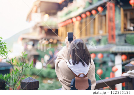 woman traveler traveling in Taiwan, female Tourist taking photo by mobile phone at Jiufen Old Street village with Tea House background. Popular landmarks and attractions near Taipei City 122555155