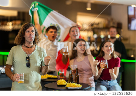 Group of friends cheer together for their favorite Mexican team in beer bar 122555626