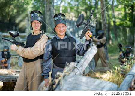 Cheerful young and adult men on paintball battleground Cheerful young and adult men on paintball battleground 122556052