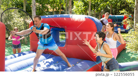 Happy man competing with friends in collect hoops on inflatable arena Happy man competing with friends in collect hoops on inflatable arena 122556055