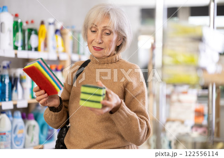 Positive mature woman choosing cleaning sponge in department store 122556114