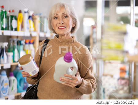 Mature positive woman consumer with household chemical products for washing indoors Mature positive woman consumer with household chemical products for washing indoors 122556225