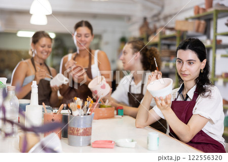 Girl painting with brush on handmade ceramic bowl Girl painting with brush on handmade ceramic bowl 122556320