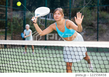 Young woman playing friendly paddleball match on outdoor court 122556438