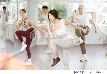 Smiling brunette practicing rhythmic aerobics in fitness studio 122556617
