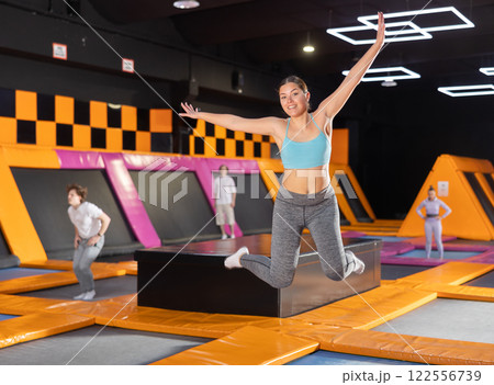 Young woman in sport clothes high jumping in trampoline arena 122556739