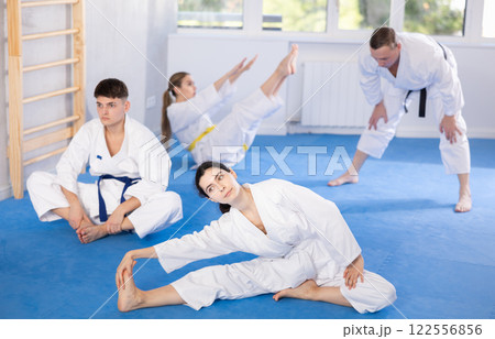 Young woman wearing kimono practicing leg stretching position in sports hall 122556856