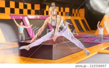 Middle-aged woman in sport clothes high jumping in trampoline arena Middle-aged woman in sport clothes high jumping in trampoline arena 122556957
