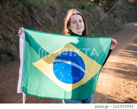 Smiling woman standing outdoors with flag of Brazil 122557043