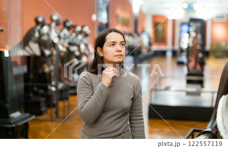 Interested woman viewing collection of medieval armor in museum Interested woman viewing collection of medieval armor in museum 122557119