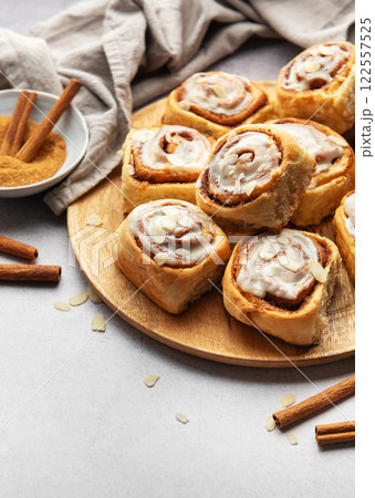 Freshly baked cinnamon rolls with icing and almond flakes on wooden plate Freshly baked cinnamon rolls with icing and almond flakes on wooden plate 122557525