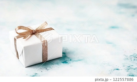 Elegant White Gift Box with Gold Ribbon on Soft Blue Background Elegant White Gift Box with Gold Ribbon on Soft Blue Background 122557886