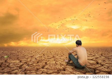 Man sit on cracked earth near dry land and hot dry air. concept of drought crisis. Man sit on cracked earth near dry land and hot dry air. concept of drought crisis. 122558156