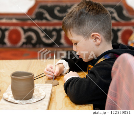 A boy creates a pot and decorating in a pottery workshop 122559051