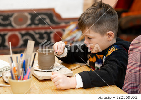 A boy creates a pot and decorating in a pottery workshop A boy creates a pot and decorating in a pottery workshop 122559052