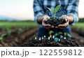 person holds small seedling in their hands, surrounded by digital icons representing growth and technology. This image symbolizes fusion of nature and innovation, highlighting importance of 122559812