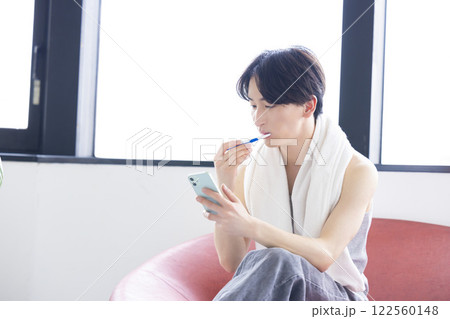ビューティーイメージ　スマホを見ながら歯磨きをする男性 122560148