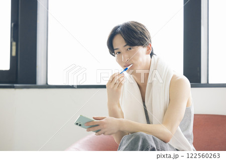 ビューティーイメージ スマホを見ながら歯磨きをする男性 ビューティーイメージ スマホを見ながら歯磨きをする男性 122560263