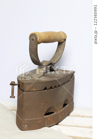 Old iron, heated by hot coals. Located on the a wooden box. 122560991