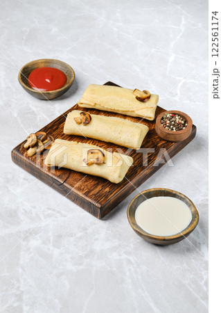 Crepes filled with mushrooms and cheese on a wooden platter Crepes filled with mushrooms and cheese on a wooden platter 122561174
