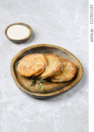 Delicious golden potato cakes served on a rustic wooden plate with dipping sauce 122561185