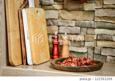 Chopped bacon served on a rustic plate in a cozy kitchen setting with wooden boards Chopped bacon served on a rustic plate in a cozy kitchen setting with wooden boards 122561209