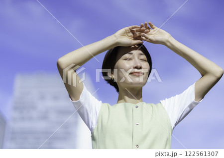 新緑の中陽射しを遮るように手を当てるミドルエイジの女性 122561307