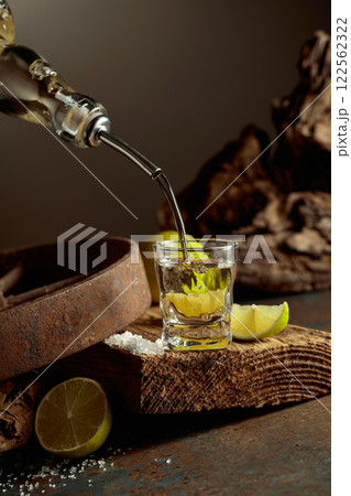 Tequila is poured from a bottle into a glass. Tequila is poured from a bottle into a glass. 122562322