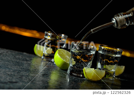 Strong alcoholic drink and lime slices on a black background. 122562326
