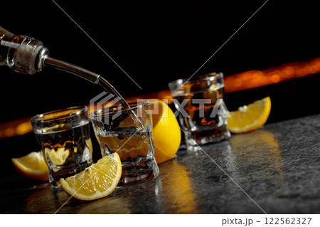 Vodka and lemon slices on a dark blue background. 122562327