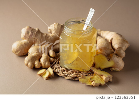 Ginger jam in small square jar and fresh ginger. 122562351