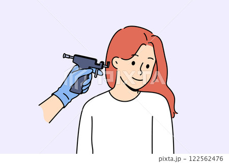 Machine for piercing ears near woman visiting cosmetologist to get opportunity to wear earrings 122562476