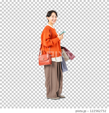 Middle-aged woman using a smartphone while holding a shopping bag. Full-body photo PNG with transparent background precisely cut by hand 122562732