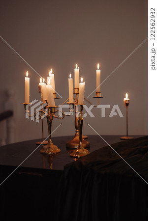 Burning candles in metal candlesticks on the table Burning candles in metal candlesticks on the table 122562932
