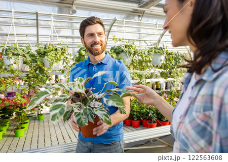 Gardener man advising male client during buying flowers in garden center Gardener man advising male client during buying flowers in garden center 122563608