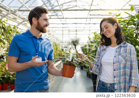 Man florist in small business nursery offering potted plants and flowers for sale to woman 122563610