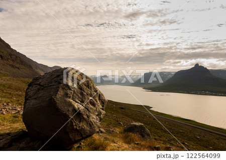 A large rock sits atop a hill overlooking a Fjord in the westfjords. Iceland 122564099