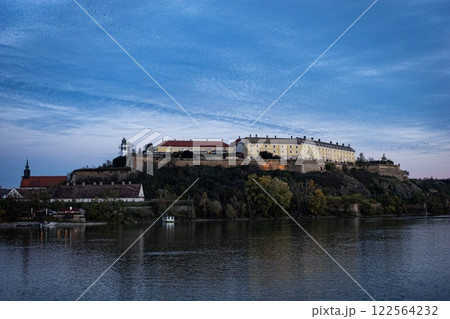 A grand castle sits atop a hill, overlooking a serene lake 122564232