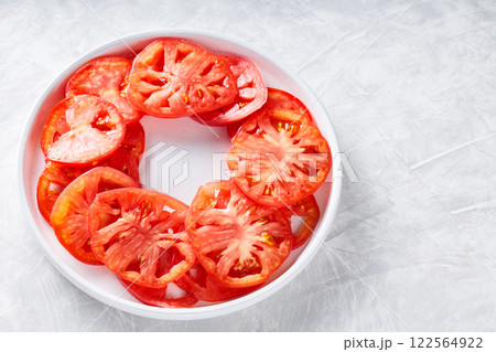 Fresh Tomato Slices Arranged in Circle on White Plate, Light Grey Textured Background, Top View, Copy Space Fresh Tomato Slices Arranged in Circle on White Plate, Light Grey Textured Background, Top View, Copy Space 122564922